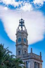 Fototapeta premium The bell tower of Ajuntament de València with a blue sky with strange clouds along Placa Del Ajuntament, Valencia, Spain