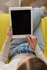 Overhead view of girl using digital tablet with blank screen on sofa