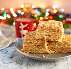 stack of slices of Napoleon cake made of puff pastry and butter cream in a gray ceramic plate