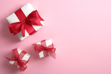 White gift boxes with red ribbon bow on pastel pink background. Saint Valentine's Day surprise, love concept. Flat lay, top view.