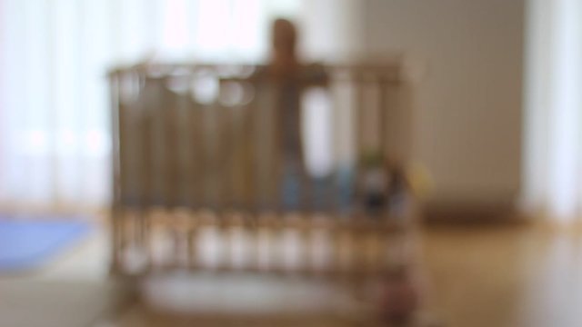 Very lonely one small boy, child in a baby cot. Out of focus. Alone. Sad. Lost.