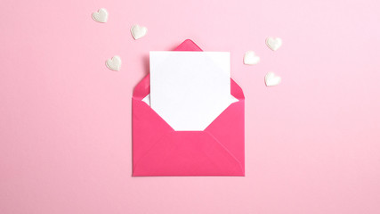 Envelope with blank white paper note inside and Valentine hearts on pink background. Romantic love...