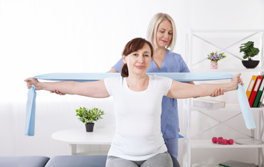 Fototapeta na wymiar Physiotherapy, sport injury rehabilitation treatment with Resistance Band. Woman having chiropractic back adjustment. Osteopathy, Alternative medicine, pain relief concept.