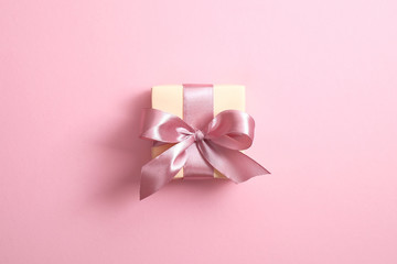 Gift box with ribbon bow on pink background. Elegant, minimal, stylish design. Valentine's, Mother's, Woman's day or birthday present.