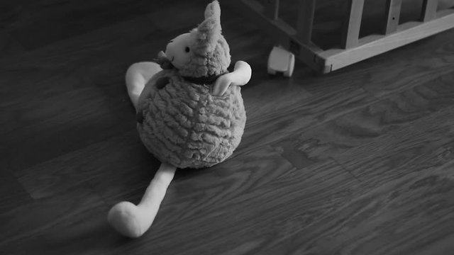Small plush toy in the front of wooden baby cot.