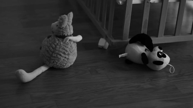 Small plush toy in the front of wooden baby cot.