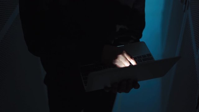 A computer programmer or hacker prints a code on a laptop keyboard to break into a secret organization system.