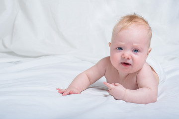 Displeased baby on his tummy. White background