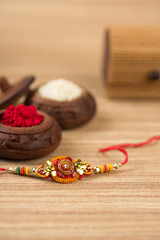 Indian festival: Raksha Bandhan background with an elegant Rakhi, Rice Grains and Kumkum. A traditional Indian wrist band which is a symbol of love between Brothers and Sisters.