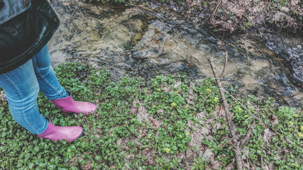Woman in pink rubber boots by the stream