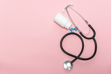 Medical stethoscope and bottle with blue pills on pink pastel background with copy space for your text Health care concept. World Health Day concept.