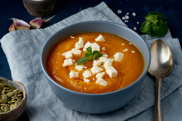 Pumpkin cream soup with feta cheese, autumn homemade food, dark blue background, side view. Fodmap diet, lchf. Vegetarian menu, clean eating recipe