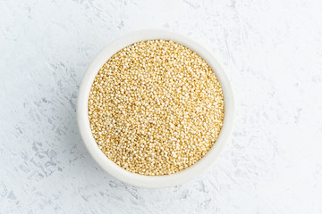 Quinoa seed in white bowl on white background. Dried cereals in cup, vegan food, fodmap diet. Top view, close up.