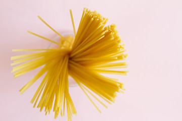 Yellow long spaghetti and pasta on pink background. Italian pasta. Raw spaghetti Bolognese. Raw spaghetti. The concept of food. Concept of Italian cuisine and menu. Flat lay.