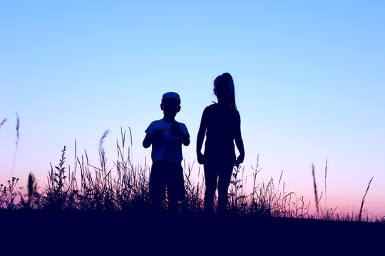 Blurry image of children playing outdoor over blue sky background. Family, childhood, friendship concept.  Kids silhouettes outdoors.