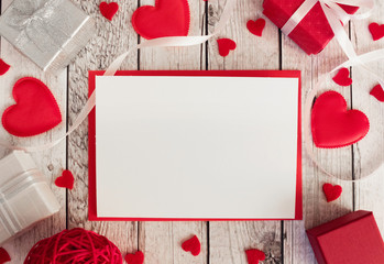 Valentines day mock up. Red envelope, red hearts, gift boxes on white wooden background. Valentines day card.