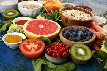 Healthy food clean eating selection: fruit, vegetable, seeds, superfood, cereals, leaf vegetable on rustic background