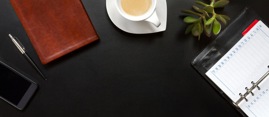 High angle view of businessman desk with organizer, pen, glasses and green plant. Top view of office supplies on blackboard background with copy space.banner