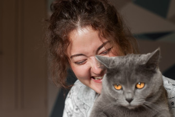 Beautiful girl playing with a gray cat