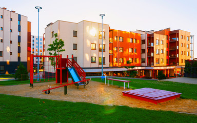 Fototapeta na wymiar Apartment residential house facade architecture with kid playground sun light reflex