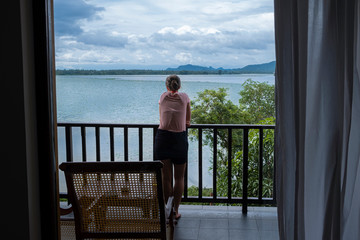 Woman leaning on a balcony cealing looking over Tissa lake, Sri Lanka