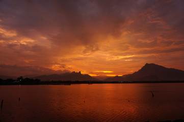 Sunset and sunrise are the natural beauty at the end of the night and at dusk giving the perfect color to the sky so the clouds look beautiful to be seen with the beach set against a mountain.