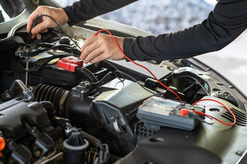 Fototapeta na wymiar Hand of mechanic man hold multimeter tool for inspection battery and maintenance car service