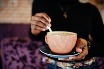 Close up african woman in black sweater with cup of hot drink.