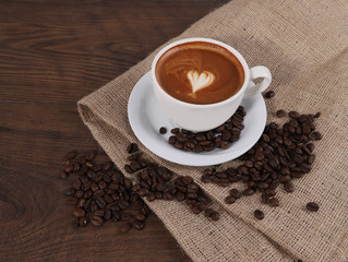 Cup of coffee, coffee bean with tablecloth on the wood table