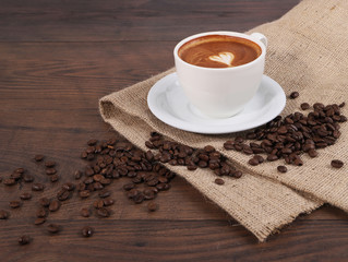 Cup of coffee, coffee bean with tablecloth on the wood table