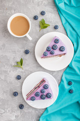 Homemade cake with souffle cream and blueberry jam with cup of coffee on a gray concrete  background. top view.
