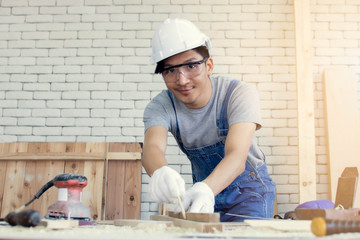 A carpenter is using pencil for marking on wood