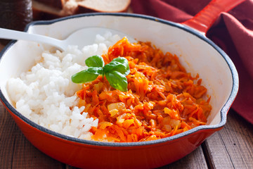 Fried carrots with onions in a pan with boiled rice, selective focus