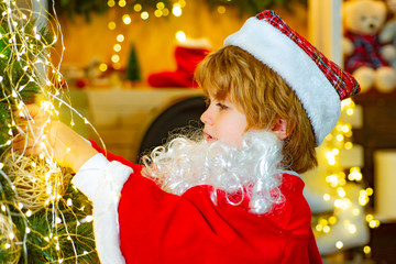 Winter fairy tale. Child decorates the Christmas tree with fabulous light. Christmas kid boy.