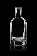 Empty open glass bottle on black background with reflection.