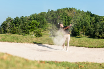 Profession asian Golfer hitting out of a sand trap. The golf course is on the sand.  Hobby in holiday and vacations on club golf. Lifestyle and Sport Concept