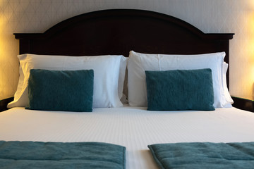 Comfortable and clean hotel room bed. Pillow and blanket on bed with lamps on the side in luxurious bedroom suite