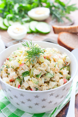 Salad with crab sticks, fresh cucumbers and rice in a white bowl, selective focus