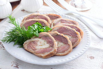 Cooked pork knuckle roll with chicken on a white plate, horizontal
