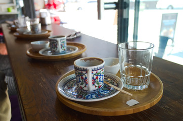 Empty cup of Turkish coffee with traditional patter in cafe and empty glass of water close up. Selective focus on first cup. Istanbul, Turkey.