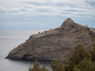 Naklejka premium Dolphin-shaped mountain cape. Autumn view of the sea coast of Crimea. Autumn landscape, beautiful mountains, sea in a cloudy day