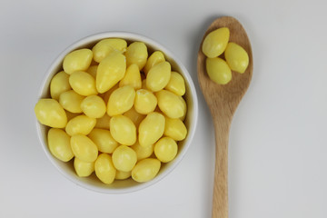 Ginkgo nuts in white bowl with spoon on white background