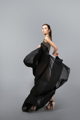 beautiful young girl in flying black dress. Flowing fabric. Light black fabric flying in the wind