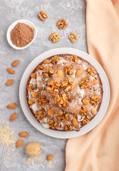 Fototapeta na wymiar Homemade cake with milk cream, cocoa, almond, hazelnut on a gray concrete background with orange textile. Top view.