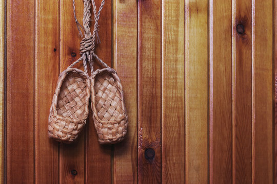 Old Russian shoes - souvenir bast shoes hanging on a light wood wall.