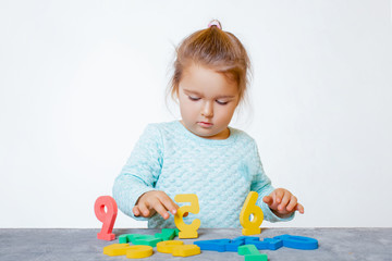Fototapeta premium Little girl Playing with Figures, early Education, Mathematics and Numeracy. close-up. Child in Studio.- Image 