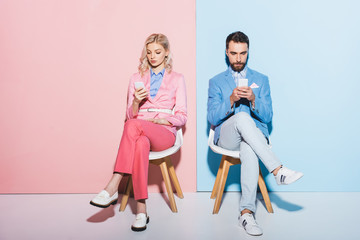 Naklejka premium attractive woman and handsome man using smartphones on pink and blue background