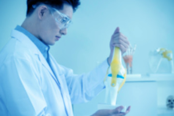 Blur image of concept of medical, chemicals or scientific laboratory research and Innovation in the laboratory. experienced handsome Asian man scientist is performing work in the laboratory.