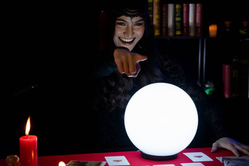 Beautiful young Asian woman Gypsy Fortune teller glowing crystal ball, tarot cards and composition...
