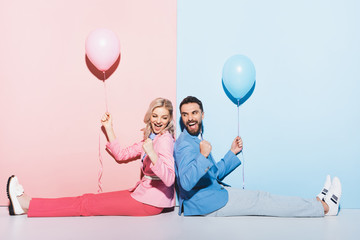 back to back view of smiling woman and handsome man with balloons showing yes gesture on pink and blue background